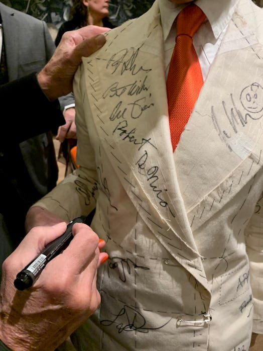 A person signing the white suit costume of Sandy Powell 