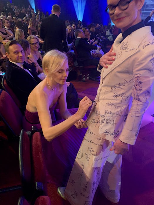 Sandy Powell taking a signature from Charlize Theron on her white suit costume