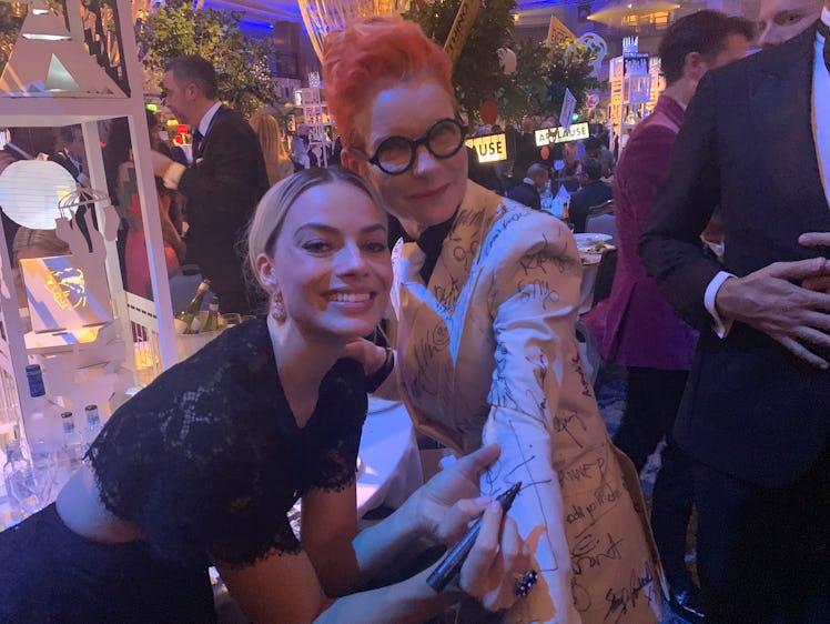 Sandy Powell taking a signature from Margot Robbie on her white suit costume