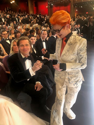 Sandy Powell taking a signature from Brad Pitt on her white suit costume