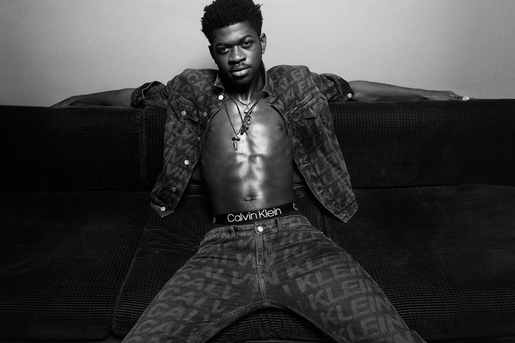 Lil Nas X posing while wearing a black combination of a CK shirt and pants
