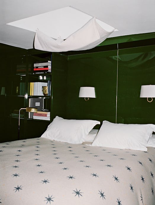 A bedroom with green walls and a white king-sized bed