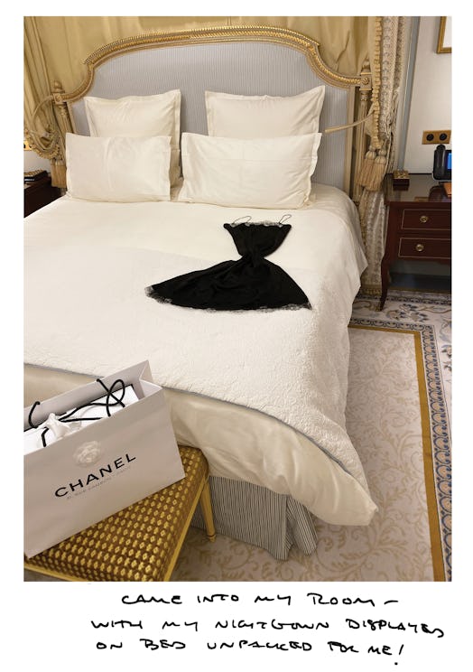 A bed with white bedsheets and a black nightgown by Chanel on it 