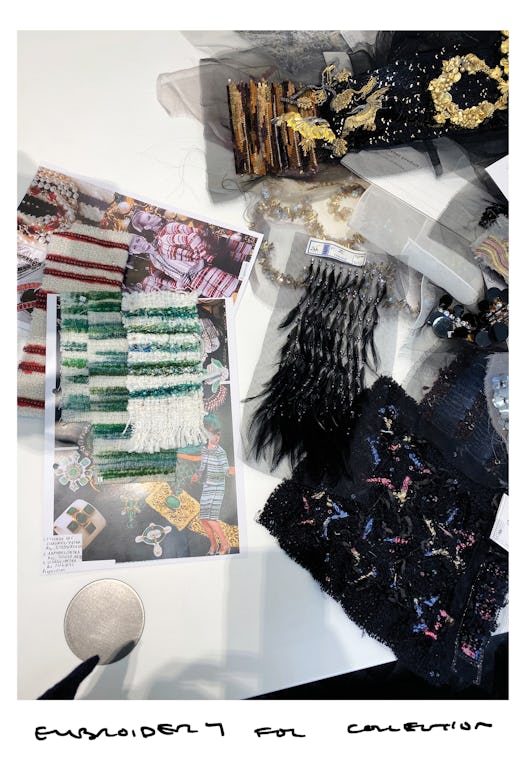 Two photographs and several pieces of fabric with embroidery by Chanel on a white table