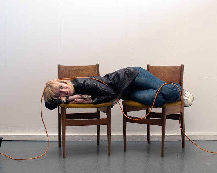 A model lying on two chairs with a rope placed over her