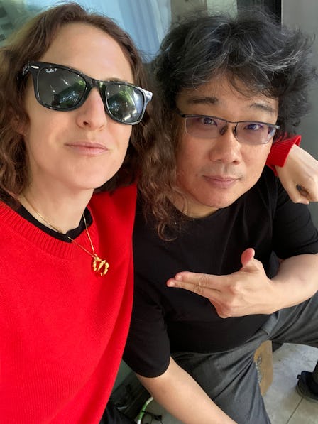 Sara Moonves in a red sweater and Bong Joon Ho in a black shirt taking a selfie