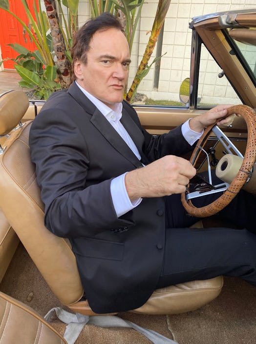 Quentin Tarantino sitting in an old time car