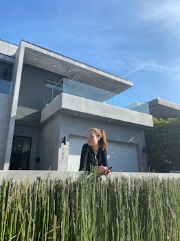 Julia McClatchy standing in front of a big grey mansion 