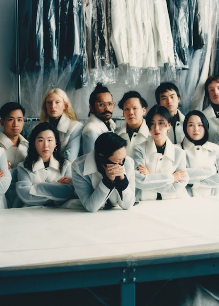 Peter Do and his team standing behind a table in white coats and clothes hanged behind them 