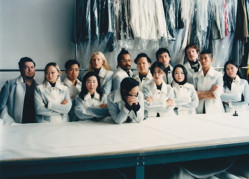 Peter Do and his team standing behind a table in white coats and clothes hanged behind them