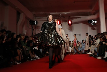 Lena Dunham wearing a leather cocktail dress while leading the runway with other models walking behi...