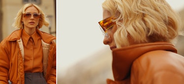 A blonde woman walking in an orange combination of a shirt and a jacket 