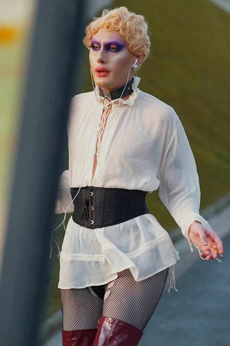 A model walking in a white mini dress with a black belt