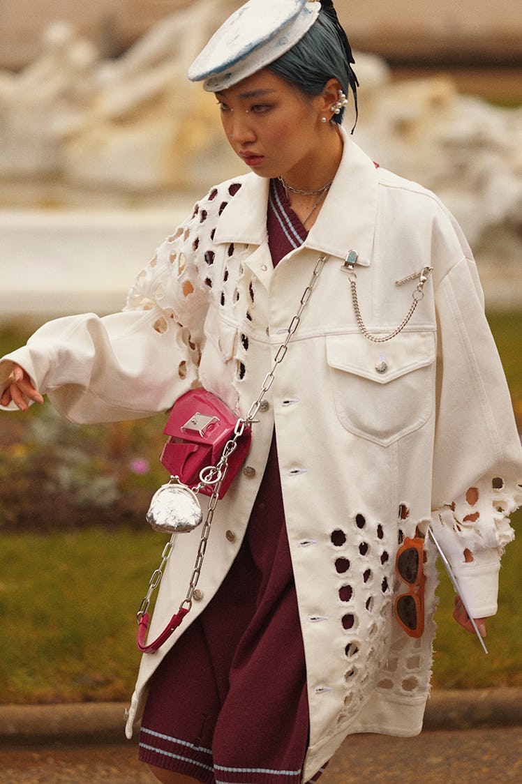 A woman walking while wearing a white coat over a purple dress