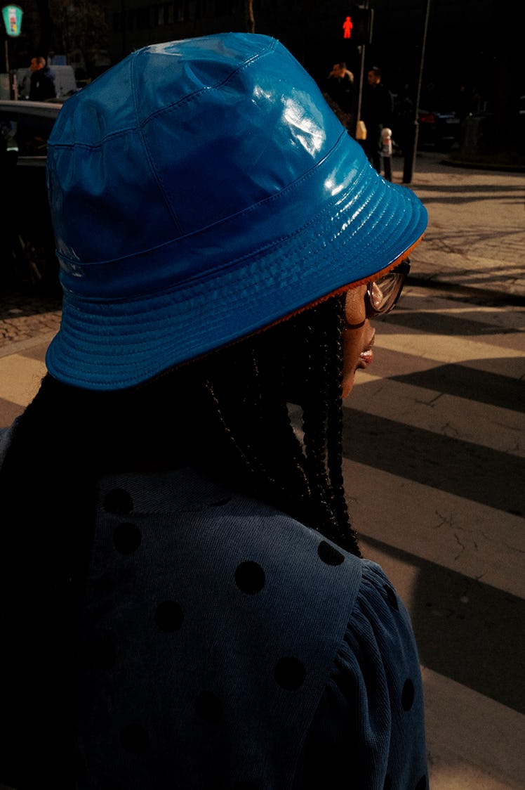 A woman walking while wearing a blue bucket hat 