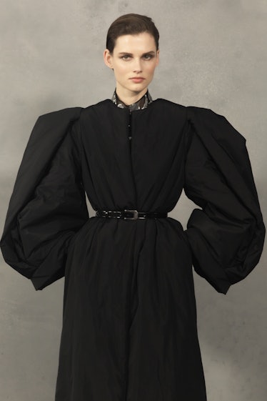 A model wearing a black coat-dress with puffy sleeves backstage at the Givenchy Fall 2020