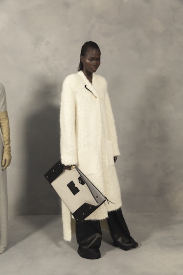 A model in a cream coat, black-white bag and black trousers backstage at the Givenchy Fall 2020