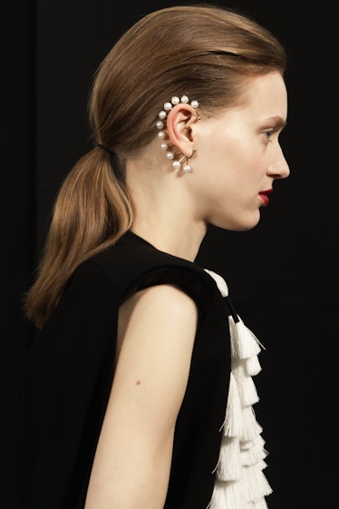 A side-profile of a model in a black-white dress and pearl ear cuff at the Givenchy Fall 2020 show