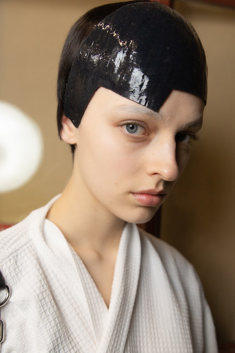 A model backstage at the Thom Browne fall 2020 show, during Paris Fashion Week in a white robe and h...