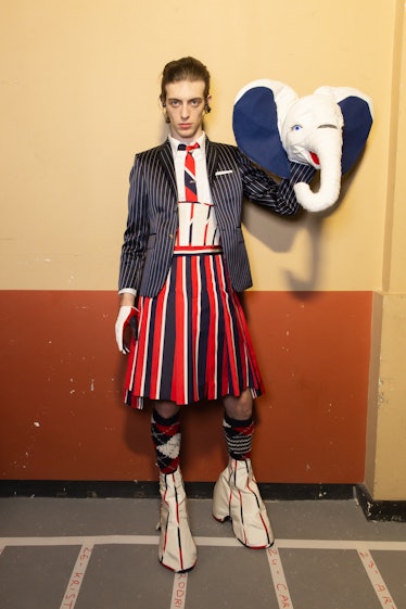 A model backstage at Thom Browne's fall 2020 show at Paris Fashion Week, holding up an elephant mask...