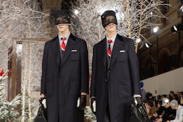 Models on Thom Browne's fall 2020 runway during Paris Fashion Week in long black jackets, red, blue ...