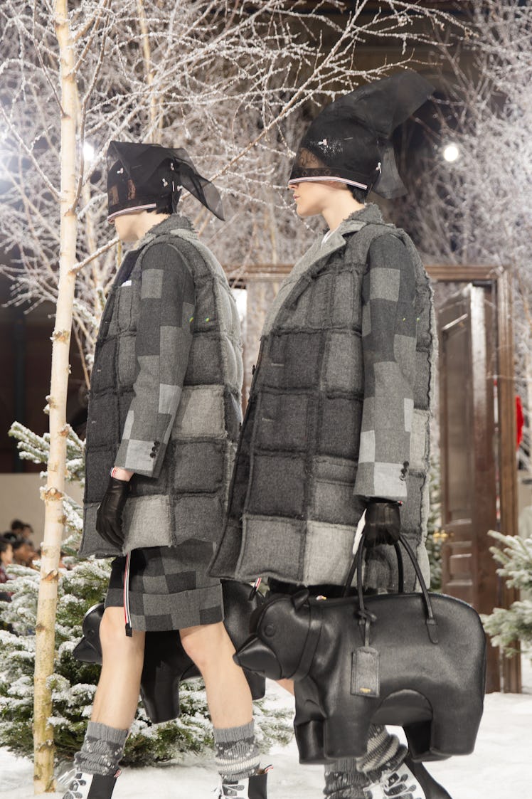 Models on Thom Browne's fall 2020 runway during Paris Fashion Week in plaid jackets carrying bear-sh...