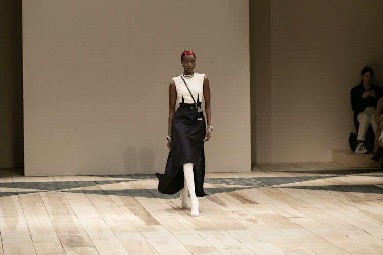 A model in a white top, black skirt and white boots at the Alexander McQueen Fall 2020 show