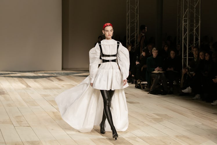 A model in a white dress with black harness at the Alexander McQueen Fall 2020 show