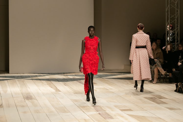 A model in a red dress and a model in a beige coat at the Alexander McQueen Fall 2020 show