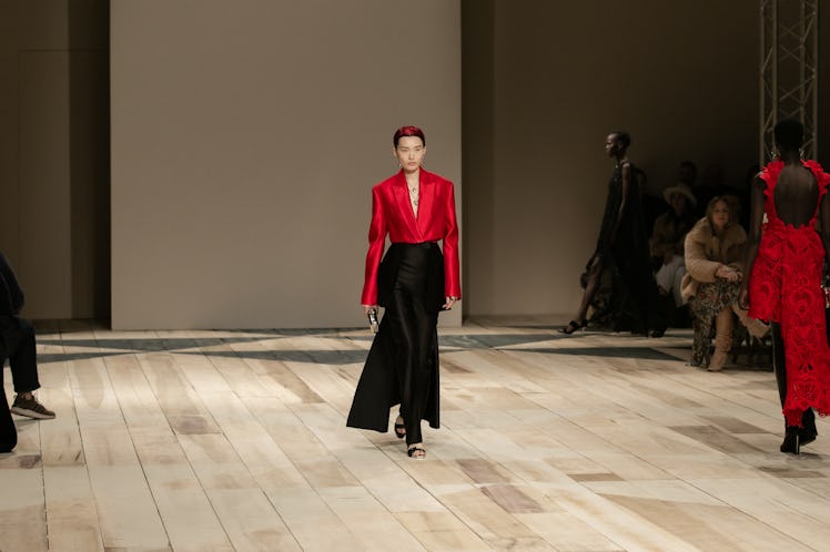 A model in a red satin jacket and black skirt at the Alexander McQueen Fall 2020 show