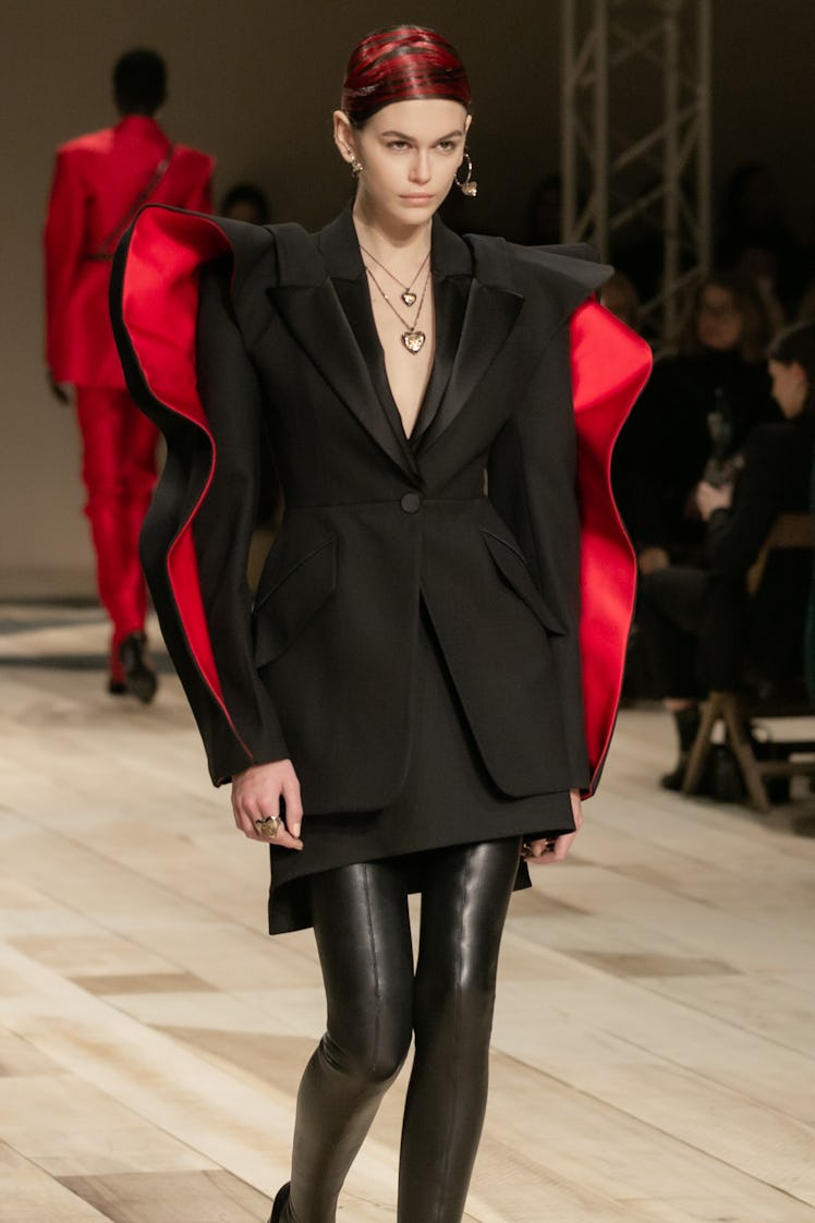 Kaia Gerber in a black coat dress and black leather trousers at the Alexander McQueen Fall 2020 show