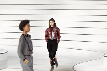 A model walking in a burgundy jacket and black trousers at the Chanel fall 2020 show