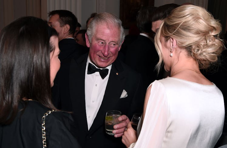 Prince Charles mingling at an event with a drink. 