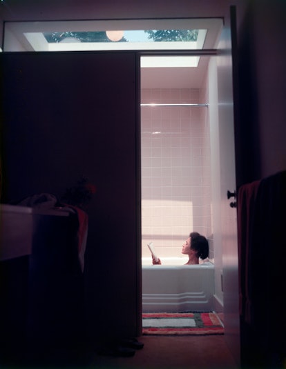 A woman reading a book while soaking in a bathtub during the quarantine