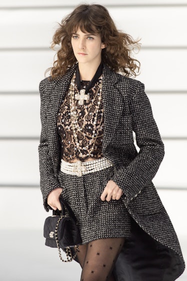 A model walking in a grey coat and shorts and black lace top at the Chanel fall 2020 show