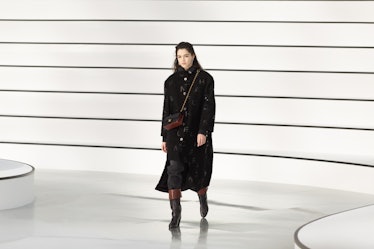 A model in a black coat and burgundy bag at the Chanel fall 2020 show