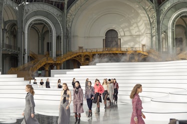 Several white steps on the runway at the Chanel fall 2020 show with models walking together in two l...