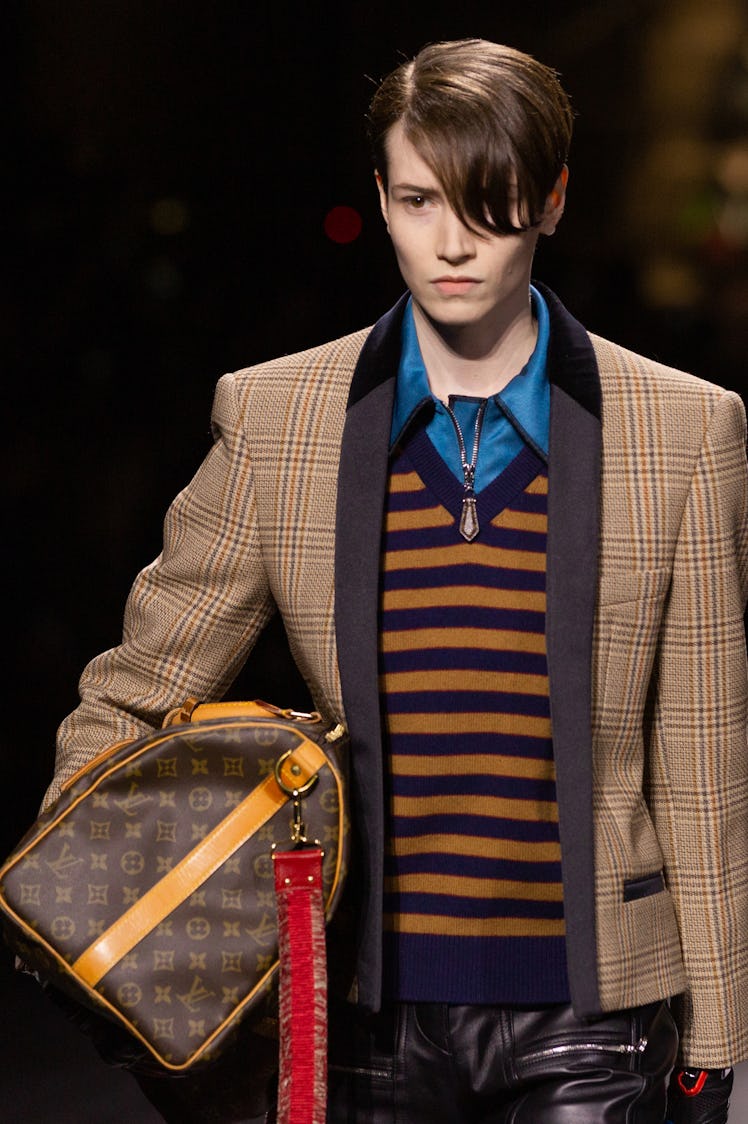 A model in a brown-black sweater and a beige-brown checked blazer and a bag at the Louis Vuitton fal...
