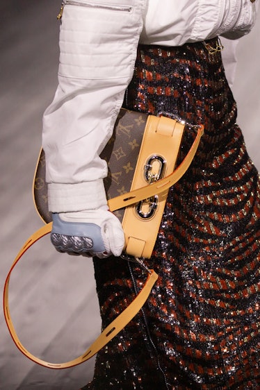 A model in a white jacket and black-brown sequin skirt carrying a brown-yellow bag at the Louis Vuit...