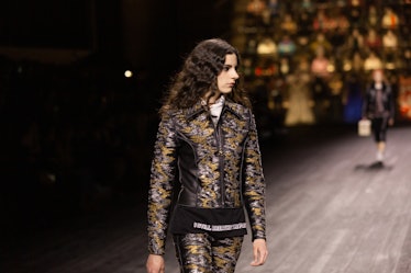 A model walking in a black-gold jacket and trousers at the Louis Vuitton fall 2020 show