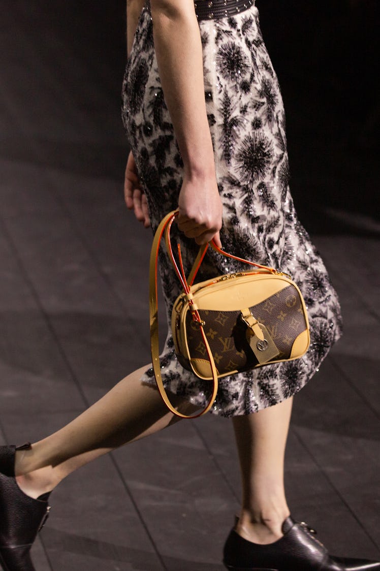 A model walking in a black-white floral dress and a brown-beige bag at the Louis Vuitton fall 2020 s...
