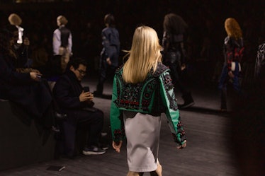 A model walking in a black-green jacket and grey skirt at the Louis Vuitton fall 2020 show