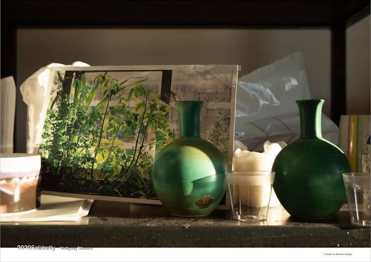 A painting of green plants and two green vases placed on a desk of a studio