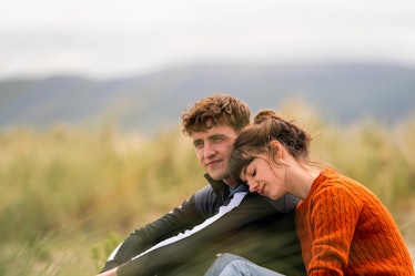 Daisy Edgar-Jones leaning on Paul Mescal's shoulder while sitting in a field 