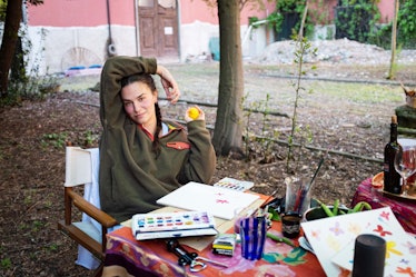 Gioia Bini at a picnic table in the back yard working on a collage 