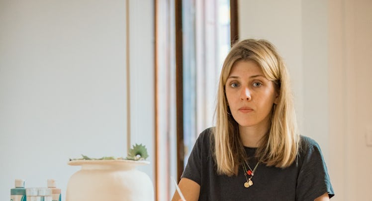 Katy Stubbs sitting at a desk and writing something with a neutral facial expression