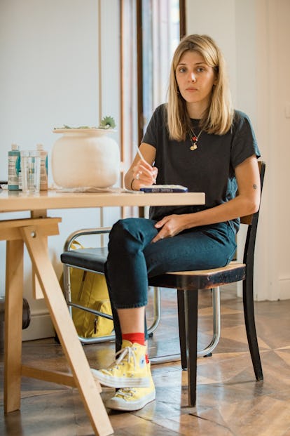 Katy Stubbs sitting at a desk and writing something with a neutral facial expression