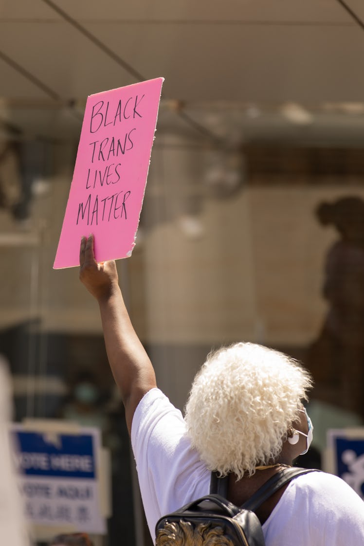 A female Brooklyn Liberation protestor holding a pink poster with "Black Trans Lives Matter" text