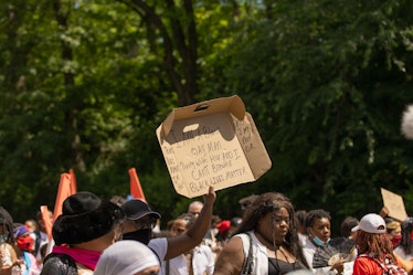 Brooklyn Liberation attendant holding a cardboard box with protest text