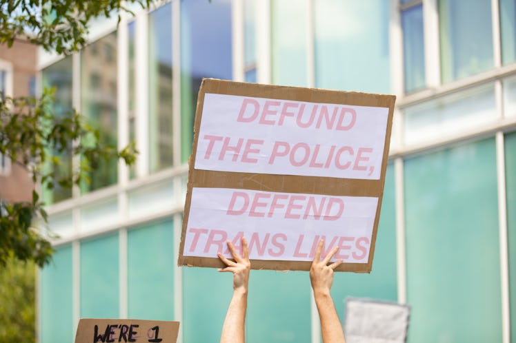 "DEFUND THE POLICE DEFEND TRANS LIVES" white protest sign